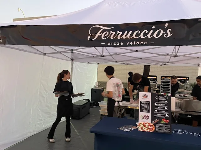 A Ferruccio's team member carrying fresh pizzas through the tent during service