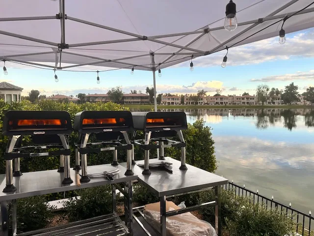 Three fire-baked pizza ovens glowing under the Ferruccio's tent at a lakeside event
