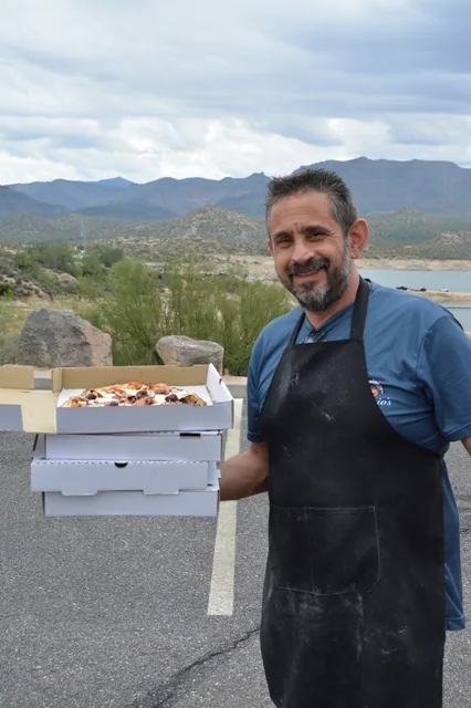 The founder carrying pizza boxes with Arizona mountains behind him
