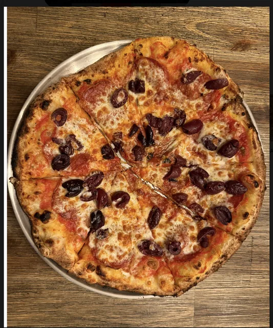 Fire-baked pizza with Kalamata olives, sliced and ready to serve