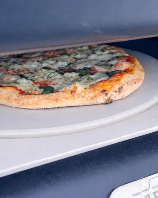 A pizza sliding onto the stone inside a Ferruccio's oven